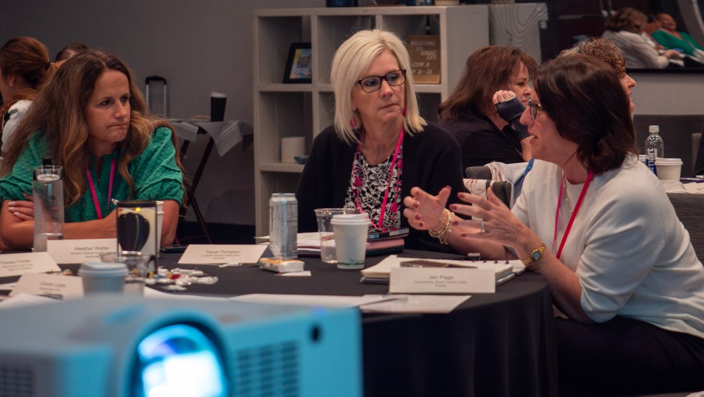 Three women in deep discussion at a CUWLA event.